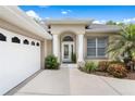 Elegant home entrance featuring decorative columns, a modern glass door, and manicured landscaping at 6106 Spinnaker Loop, Lady Lake, FL 32159