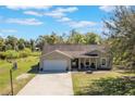 Charming single-Gathering home featuring a two-car garage and a cozy front porch, set on a sprawling lawn with mature trees at 6679 Cr 613, Bushnell, FL 33513