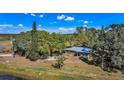 Aerial view of a single-story brick home surrounded by mature trees and green grass at 6988 Blue Cedar Rd, Leesburg, FL 34748