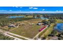 Expansive aerial view of a property including a home, barn, lake, and large open field at 6988 Blue Cedar Rd, Leesburg, FL 34748