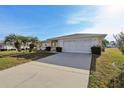 The house boasts a long driveway that leads to a two-car garage, complemented by palm trees in the front yard at 9857 Sw 63Rd Ct, Ocala, FL 34476