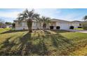 Charming single-story home with a front lawn featuring palm trees and decorative heron statues at 9857 Sw 63Rd Ct, Ocala, FL 34476
