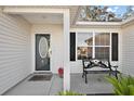 Inviting front porch features a decorative bench, attractive oval window front door and manicured landscaping at 1419 Valparaiso St, The Villages, FL 32162