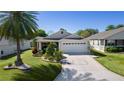 Charming single-story home with a well-manicured lawn, a palm tree, and a two-car garage at 2186 Quinn Ln, The Villages, FL 32162