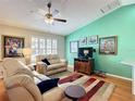 Comfortable living room featuring hardwood floors, plush seating, and vibrant accent wall with decorative art at 2250 Peak Pl, The Villages, FL 32162