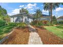 Beautiful one-story home with a lush front yard, colorful floral arrangements and a brick walkway to the front door at 590 Sandlake Ct, Mount Dora, FL 32757