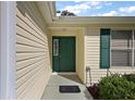 Inviting front entrance with a green door, beige siding and matching shutters at 604 Juanita Ct, The Villages, FL 32159