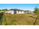 Spacious backyard featuring a black metal fence, lush green grass, and a cozy patio seating area at 1188 Oak Valley Dr, Auburndale, FL 33823