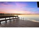 Waterfront dock featuring bench seating, ladder access, and stunning views of the serene lake at sunset at 15749 Acorn Cir, Tavares, FL 32778