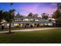 Sprawling gray single-Gathering home boasts a large manicured lawn and elegant architectural details at 15749 Acorn Cir, Tavares, FL 32778