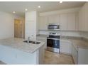 Bright kitchen features stone countertops, stainless appliances, and white cabinets, creating a modern cooking space at 2003 Firethorn Loop, Haines City, FL 33844