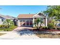 Charming single-Gathering home with a two-car garage, brick driveway, and beautifully manicured landscaping at 329 Alcove Dr, Groveland, FL 34736