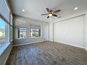 Bright and airy living room with wood-look tile flooring, multiple windows, and a stylish ceiling fan at 329 Alcove Dr, Groveland, FL 34736