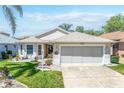 Inviting single-Gathering home features a large two-car garage, green lawn, and manicured landscaping at 5441 Sea Leopard St, Tavares, FL 32778