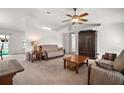 Bright living room featuring neutral carpet, a ceiling fan, and classic wood furniture at 12370 Se 100Th Ct, Belleview, FL 34420