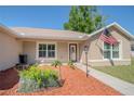 Charming home entrance with a red door, tidy landscaping, and an American flag at 13662 Se 55Th Ave, Summerfield, FL 34491