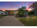 Twilight view of the home featuring carport, lush landscaping, and a walkway to the front door at 1541 Doral Cir, Lady Lake, FL 32159