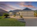 Charming home featuring a well-manicured lawn, beautiful landscaping, and an attached two car garage at 1589 Armstrong Ave, The Villages, FL 32163