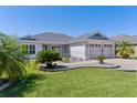 Charming home featuring a well-manicured lawn, beautiful landscaping, and an attached two car garage at 1589 Armstrong Ave, The Villages, FL 32163