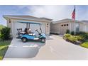 Image of a stylish blue ICON golf cart and the home's two-car and single car garages at 3641 Arlington Ridge Blvd, Leesburg, FL 34748