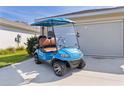 Image of a stylish blue ICON golf cart, perfect for cruising the neighborhood, and an exterior garage door at 3641 Arlington Ridge Blvd, Leesburg, FL 34748