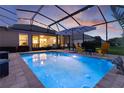 Inviting screened-in pool with ambient lighting, patio furniture, and umbrella, perfect for relaxing evenings and outdoor entertainment at 3641 Arlington Ridge Blvd, Leesburg, FL 34748