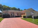 Inviting single-story home boasting a beautiful brick driveway and well-maintained landscaping with lush green lawn at 5008 Sawgrass Lake Cir, Leesburg, FL 34748
