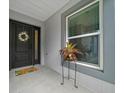 Inviting front porch with a dark front door, cheerful wreath, and a decorative plant stand at 5549 Millican Ave, The Villages, FL 32163
