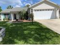 Single-story home with a well-manicured lawn, attached garage, and freshly painted exterior at 664 San Pedro Dr, The Villages, FL 32159