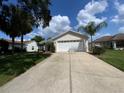 Charming single-story home with a long driveway and well-manicured lawn with palms in the yard at 664 San Pedro Dr, The Villages, FL 32159