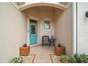 Inviting front porch with a chair, table, and decorative plants near a vibrant front door at 971 Caribou Way, The Villages, FL 32162