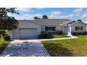 Charming white house showcasing a well-maintained lawn and decorative driveway at 9948 Se 175Th Pl, Summerfield, FL 34491