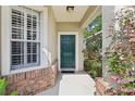 Close-up of the front door entrance showcasing brick accents and lush surrounding greenery at 1022 Saint Ives Ct, Mount Dora, FL 32757