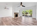 Well-lit living room with wood floors, brick fireplace, ceiling fan, and sliding glass doors at 1051 S Highland St # 4B, Mount Dora, FL 32757