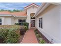 Inviting front entrance with a red brick walkway and a decorative red door and manicured shrubs at 11497 Sw 82Nd Court Rd, Ocala, FL 34481