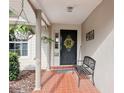 Inviting front door with a black door, brick floor, hanging plants and bench seating at 1202 Bly Ct, Eustis, FL 32726