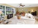 Bright living room with large windows, neutral carpet, ceiling fan, and comfortable seating at 1202 Bly Ct, Eustis, FL 32726