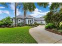 Well-maintained single-story home with a lush green lawn and a curved driveway lined with mature trees at 13112 Luntz Point Ln, Windermere, FL 34786