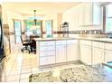 Well-lit kitchen with granite countertops, white cabinetry, modern appliances, and a cozy breakfast nook at 1312 Corona Ave, The Villages, FL 32159