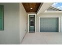 Inviting front door with glass detailing, next to a garage and under a wood-paneled porch ceiling at 137 E Palmetto Ave, Howey In The Hills, FL 34737