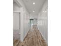 Bright hallway with decorative paneling and wood-look flooring leading to the rest of the home at 137 E Palmetto Ave, Howey In The Hills, FL 34737