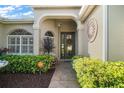 Inviting entrance with stone walkway, lush landscaping, decorative windows, and sunburst wall art accents at 1723 Carrera Dr, The Villages, FL 32159