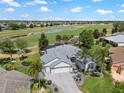 Stunning aerial view of a home situated on a golf course with a serene lake and mature trees at 1992 Hagood Loop, The Villages, FL 32162