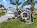 Lovely home featuring a lush lawn, mature landscaping, and a paver driveway at 1992 Hagood Loop, The Villages, FL 32162