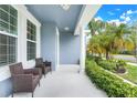 Inviting front porch with comfortable seating and views of the lush landscaping and beautiful blue painted facade at 251 Blue Cypress Dr, Groveland, FL 34736