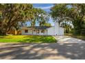 Inviting single-story home features a freshly painted white exterior, well-manicured lawn, and shade trees at 2517 Royal Palm Dr, Edgewater, FL 32141
