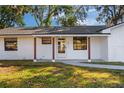 Inviting front porch of a white brick home, features stained wood columns, a glass front door, and manicured lawn at 2517 Royal Palm Dr, Edgewater, FL 32141