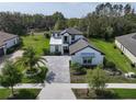 Aerial view of a modern two-story home with a brick driveway, lush landscaping, and an expansive green lawn at 25962 High Hampton Cir, Sorrento, FL 32776