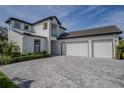 Contemporary two-story home with white exterior, two-car garage, dark trim, and a spacious, patterned brick driveway at 25962 High Hampton Cir, Sorrento, FL 32776