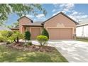 Home exterior showcases a spacious driveway leading to a two-car garage, enhanced by manicured landscaping at 3048 New Haven Pl, Mount Dora, FL 32757
